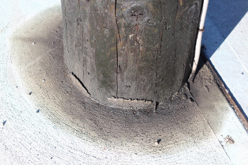 A conventional, creosote utility pole leeching chemicals into a concrete sidewalk.